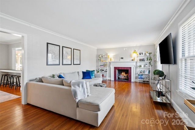 living room featuring a brick fireplace, wood-type flooring, and ornamental molding