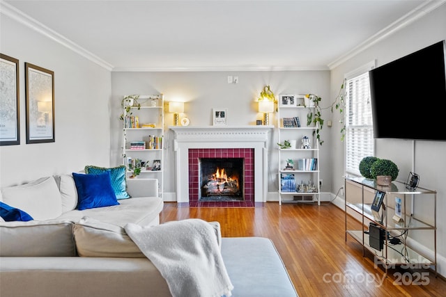 living room featuring crown molding, baseboards, wood finished floors, and a tile fireplace