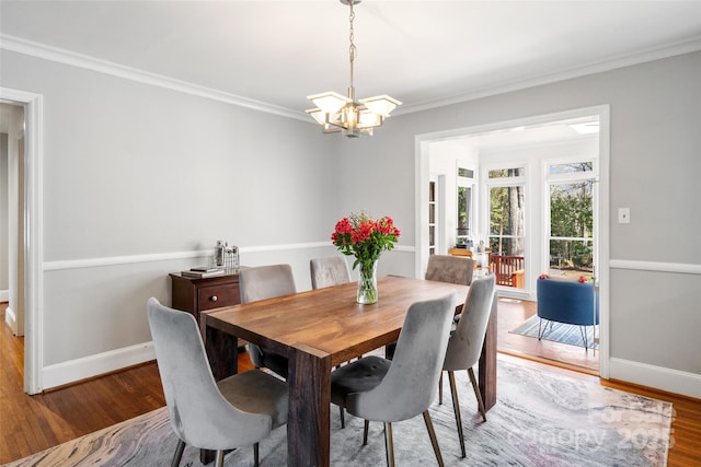 dining area featuring ornamental molding, an inviting chandelier, baseboards, and wood finished floors