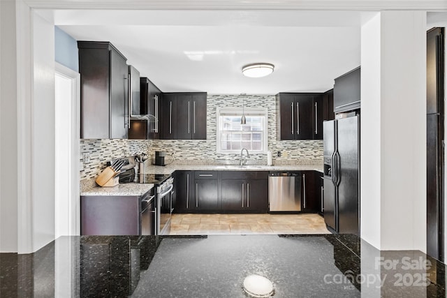 kitchen with stainless steel appliances, a sink, light stone counters, and tasteful backsplash