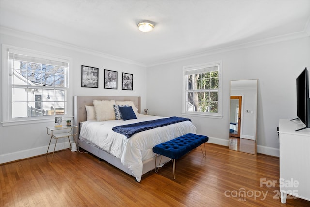 bedroom featuring baseboards, wood finished floors, and crown molding