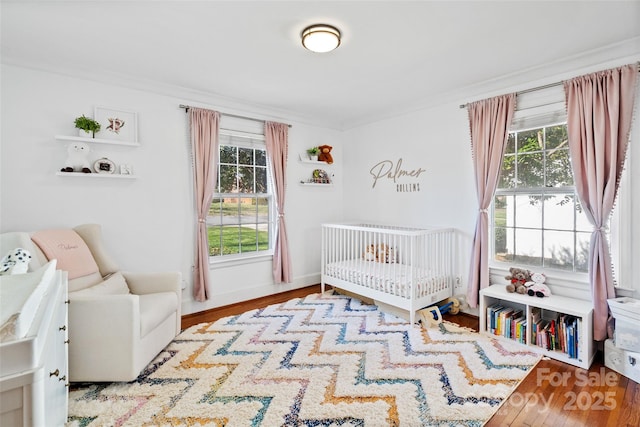 bedroom featuring multiple windows, ornamental molding, and wood finished floors