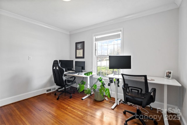 home office with baseboards, wood-type flooring, visible vents, and crown molding