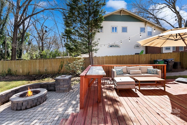 wooden deck featuring a fenced backyard and an outdoor living space with a fire pit