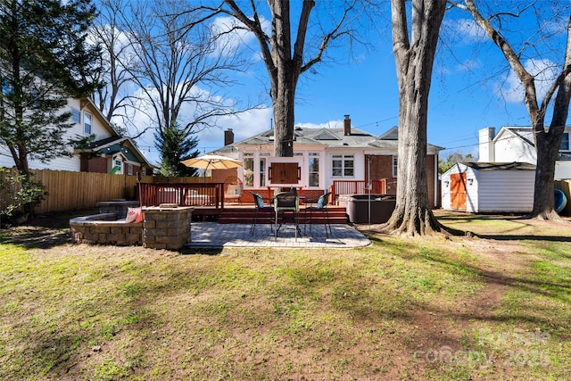 back of house with an outdoor fire pit, brick siding, fence, and a storage shed