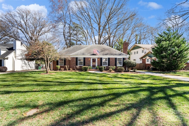 view of front facade with brick siding, a front lawn, and a chimney