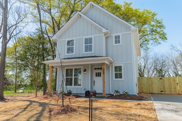 view of front facade featuring board and batten siding, a porch, and fence