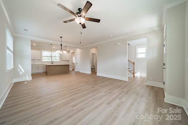 unfurnished living room featuring crown molding, ceiling fan, light wood-style floors, and baseboards