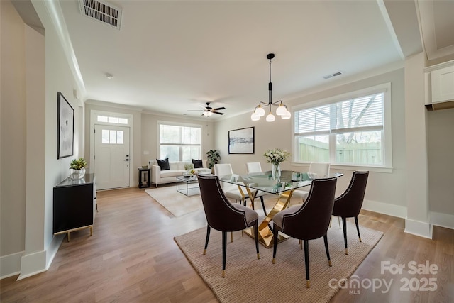 dining room with light wood-style flooring, crown molding, and visible vents