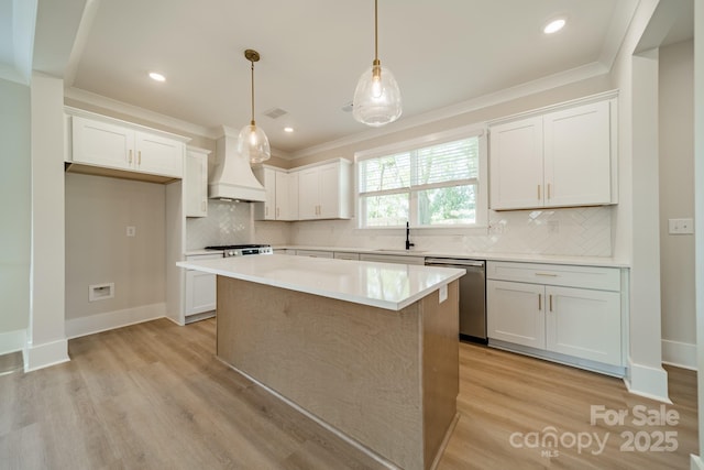 kitchen featuring custom exhaust hood, stainless steel dishwasher, light wood-type flooring, and a kitchen island