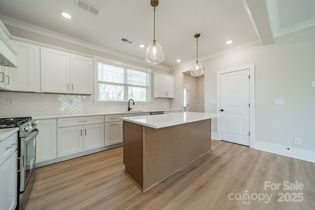 kitchen featuring ornamental molding, visible vents, stainless steel range with gas stovetop, and a kitchen island