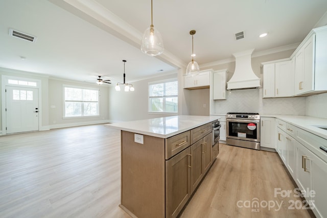 kitchen with visible vents, ornamental molding, stainless steel gas stove, custom range hood, and light wood-style flooring