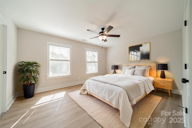 bedroom with visible vents, light wood-style flooring, a ceiling fan, and baseboards