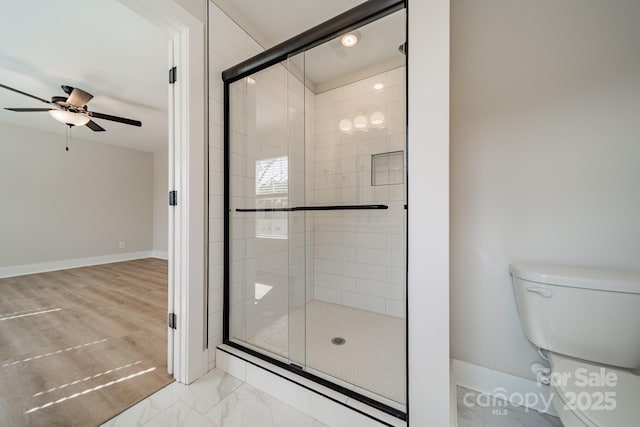 bathroom featuring toilet, marble finish floor, a ceiling fan, and a stall shower