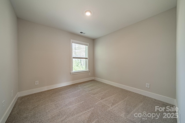 empty room with visible vents, baseboards, and light colored carpet