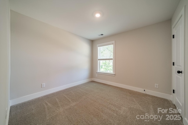 spare room with carpet floors, visible vents, and baseboards