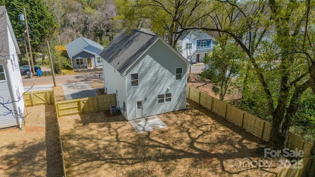 back of property with central air condition unit, a shingled roof, and a fenced backyard