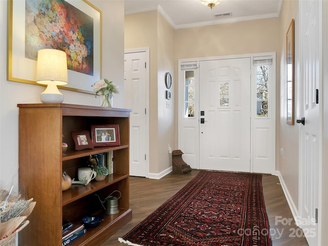 entryway featuring baseboards, wood finished floors, visible vents, and crown molding