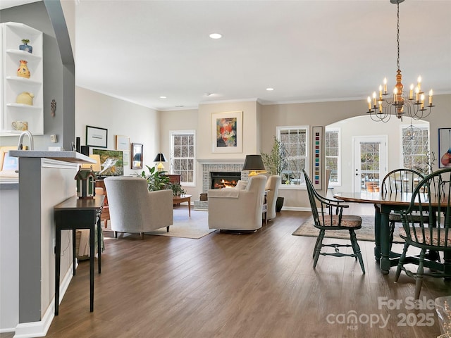 living room featuring a lit fireplace, dark wood-style flooring, plenty of natural light, and crown molding