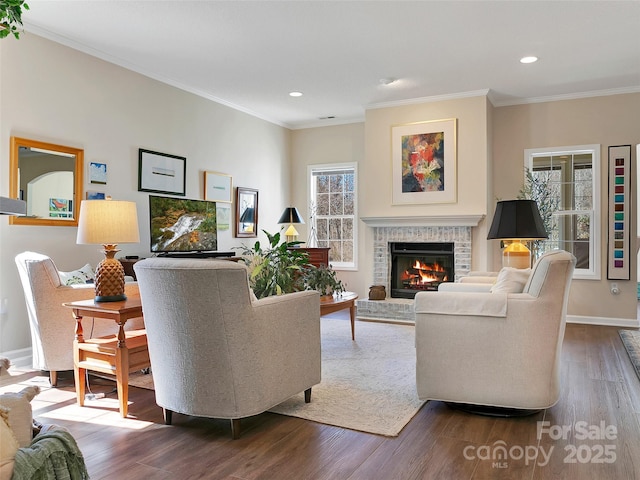 living room with a brick fireplace, crown molding, and wood finished floors