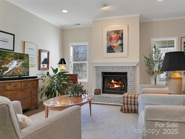 living room featuring a fireplace, visible vents, crown molding, and wood finished floors