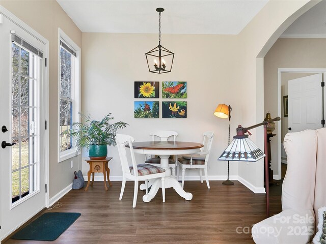 dining space featuring a wealth of natural light, arched walkways, and wood finished floors