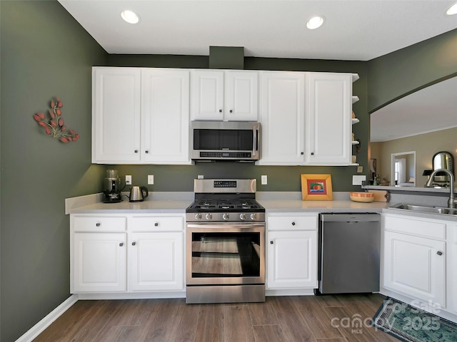 kitchen featuring stainless steel appliances, dark wood-type flooring, a sink, white cabinets, and light countertops