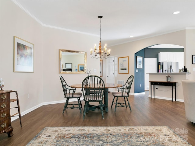 dining area featuring ornamental molding, arched walkways, dark wood finished floors, and baseboards