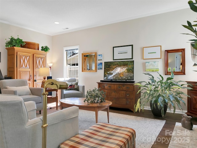 living room featuring ornamental molding, visible vents, baseboards, and wood finished floors