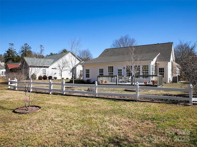 back of property with fence, central AC unit, and a lawn