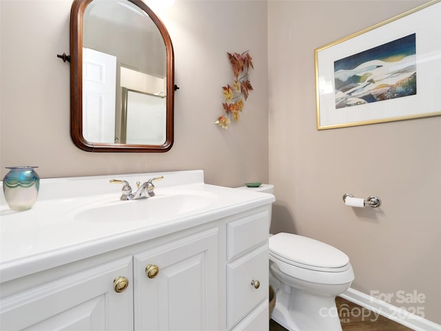 bathroom featuring toilet, baseboards, and vanity