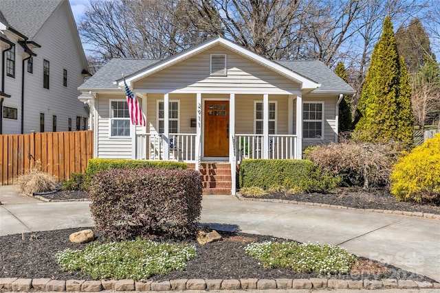 bungalow-style house with covered porch, roof with shingles, and fence