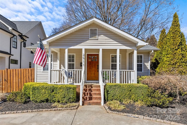 bungalow-style home with covered porch and fence