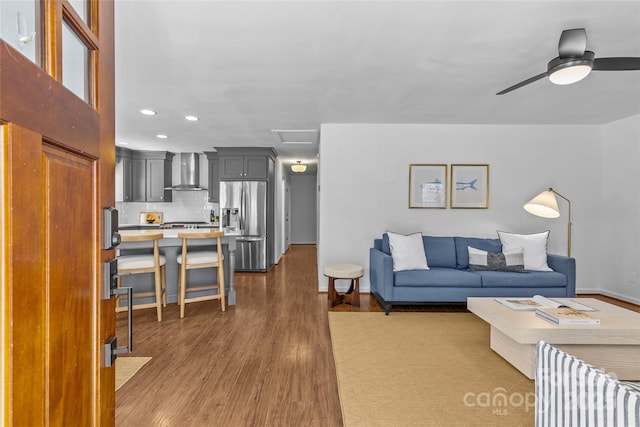 living room featuring ceiling fan, recessed lighting, wood finished floors, baseboards, and attic access