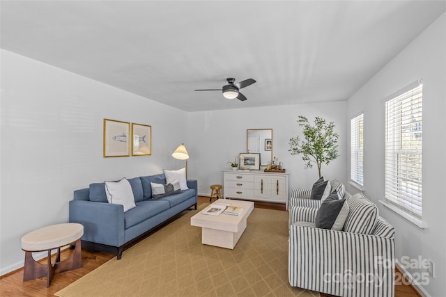 living room featuring a ceiling fan, baseboards, and wood finished floors