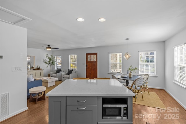 kitchen featuring gray cabinetry, visible vents, light wood-type flooring, a wealth of natural light, and stainless steel microwave