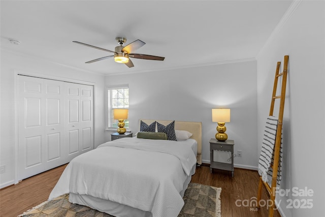 bedroom featuring crown molding, a closet, a ceiling fan, wood finished floors, and baseboards