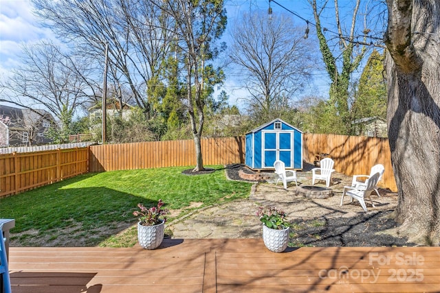 view of yard featuring a storage shed, a fenced backyard, a fire pit, and an outdoor structure