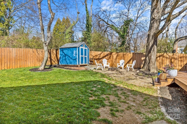 view of yard with a storage shed, a fenced backyard, a fire pit, and an outbuilding