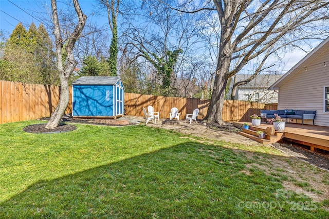 view of yard with an outbuilding, a deck, a fenced backyard, a shed, and an outdoor living space with a fire pit