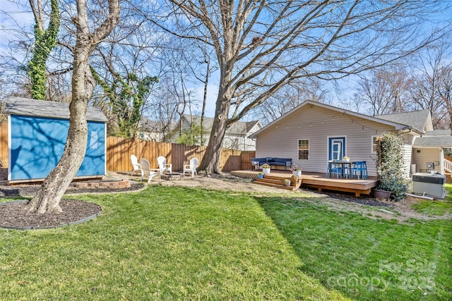 view of yard with a fenced backyard, an outdoor structure, a deck, and a shed