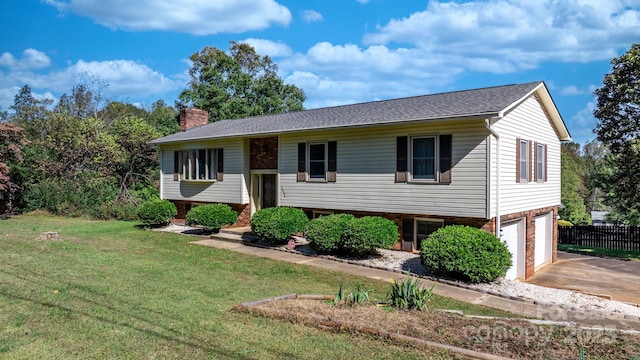 bi-level home featuring a chimney, concrete driveway, an attached garage, fence, and a front lawn