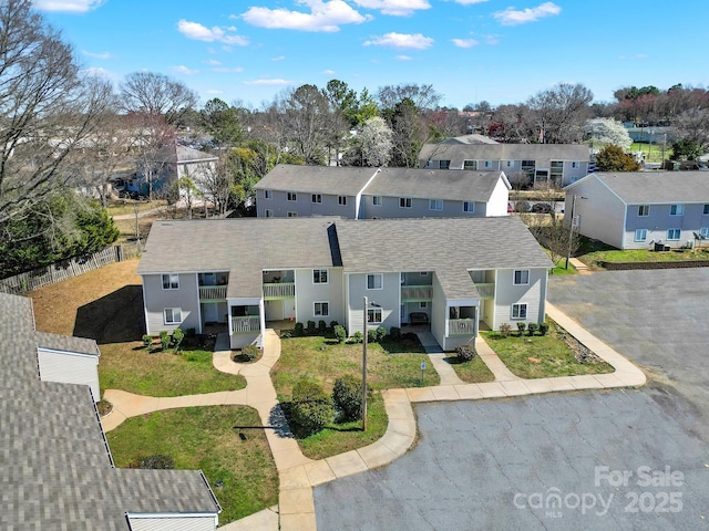 view of front of home featuring a shingled roof, a residential view, fence, and a front yard