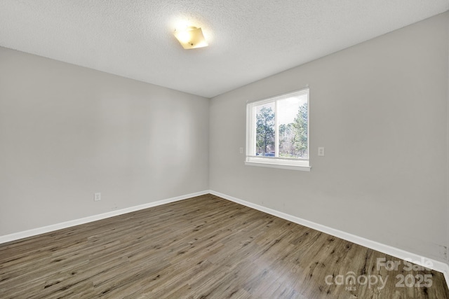 spare room featuring a textured ceiling, baseboards, and wood finished floors