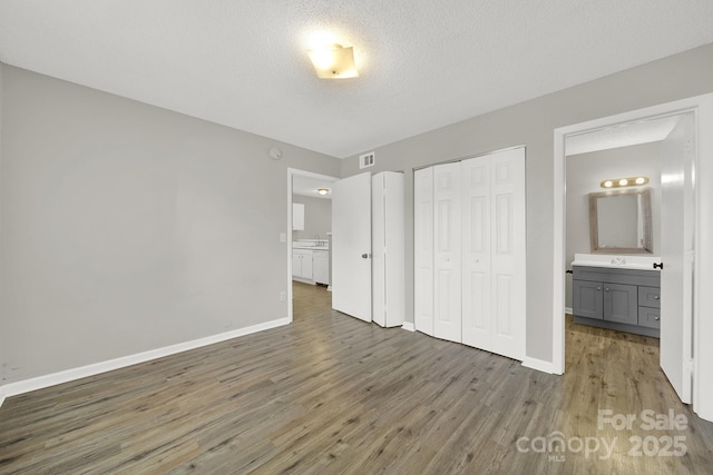 unfurnished bedroom featuring a closet, wood finished floors, visible vents, and baseboards