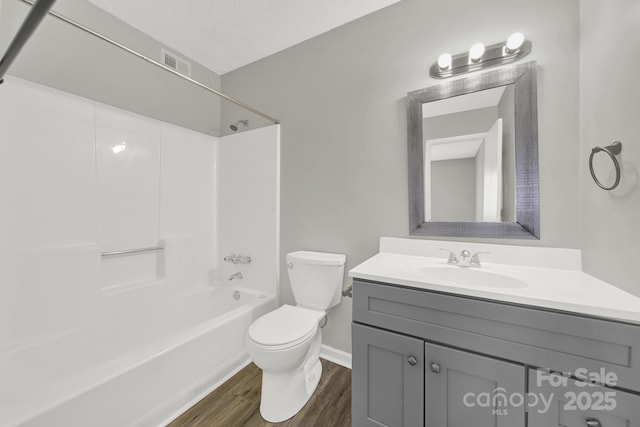 full bath with visible vents, wood finished floors,  shower combination, a textured ceiling, and vanity