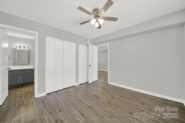 unfurnished bedroom with a closet, visible vents, a sink, wood finished floors, and baseboards