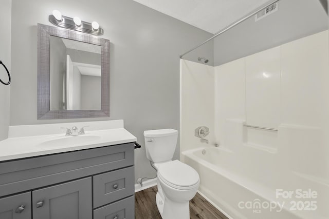 full bathroom with shower / washtub combination, visible vents, toilet, vanity, and wood finished floors