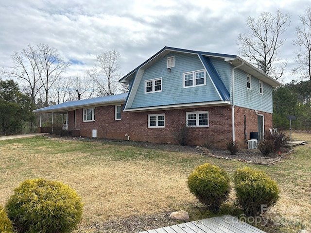 rear view of house featuring ac unit, brick siding, a lawn, and a gambrel roof