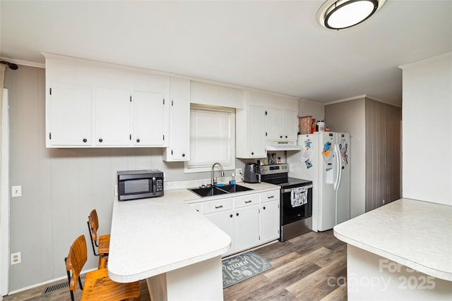 kitchen featuring white refrigerator with ice dispenser, light countertops, stainless steel range with electric cooktop, black microwave, and a sink